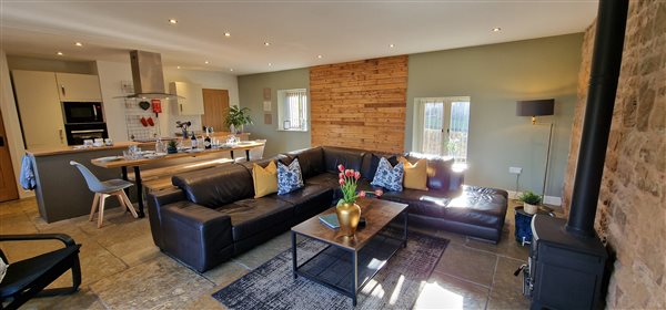 l shaped sofa, log burner and the kitchen diner behind